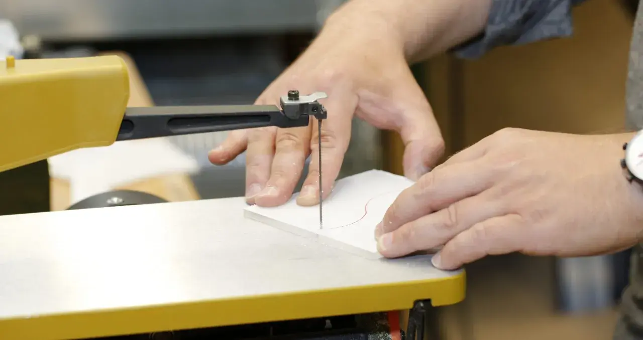Präzises acrylglas schneiden mit einer Stichsäge. Hände führen das Material entlang der roten Schnittlinie.
