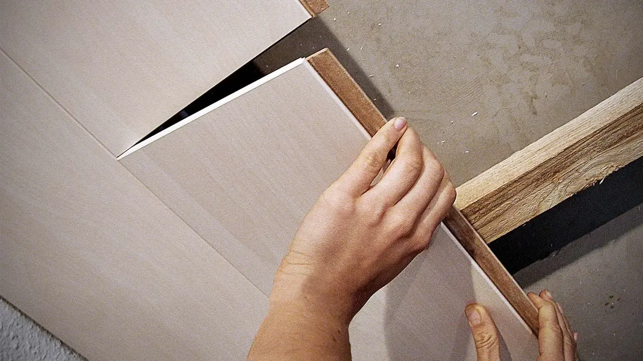 Hände bringen Deckenpaneele an, ohne Unterkonstruktion. Die Paneele werden direkt an die Decke geklebt oder geschraubt.