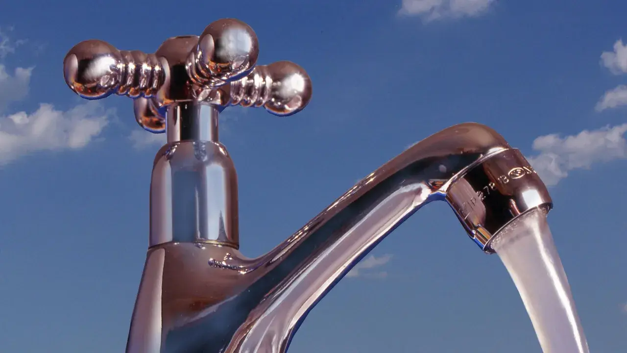 Chromhahn mit laufendem Wasser vor blauem Himmel. Der Wasserdruck ist gut, die **druck wasserleitung** liefert kräftig.