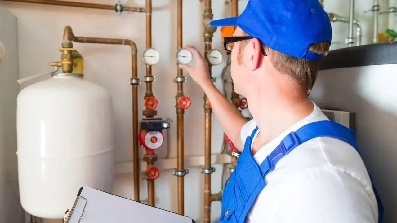 Techniker prüft Heizungsanlage, um das Heizung Wasser ablassen zu können. Er kontrolliert Manometer an Kupferrohren.