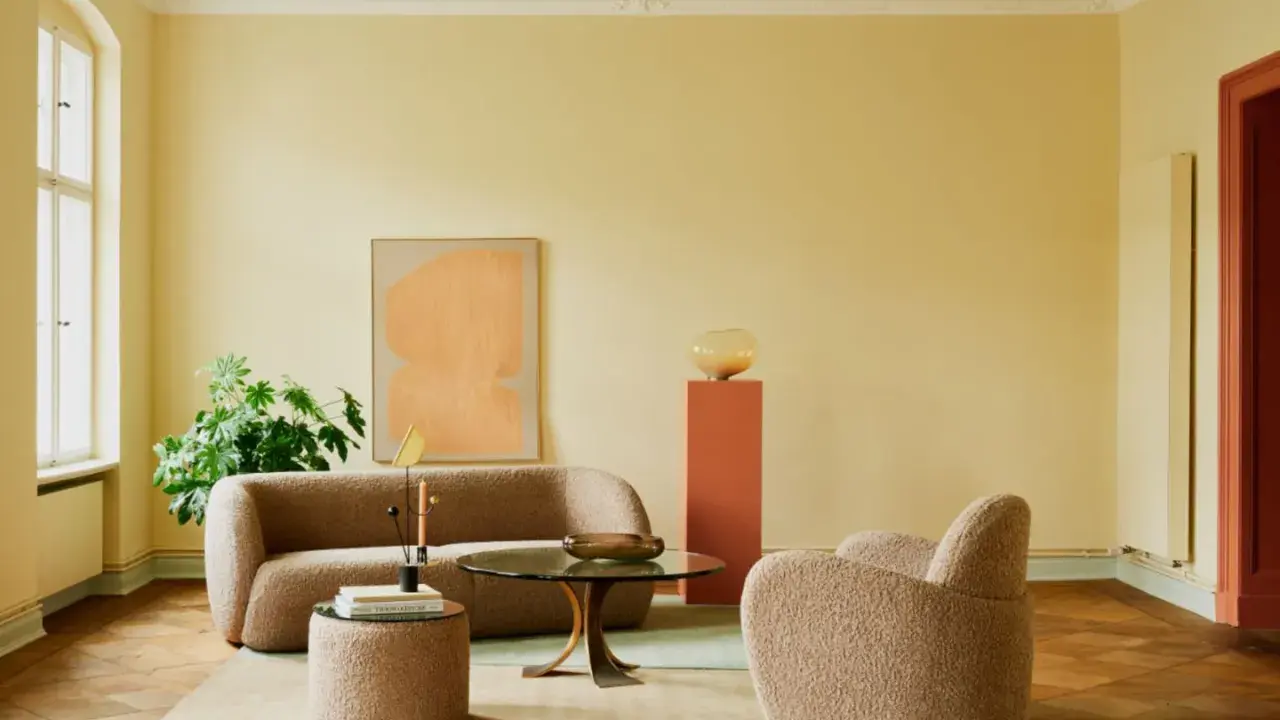 Ein Wohnzimmer mit gelben Wänden und einer grünen Decke, die frisch gestrichen wurde. Gemütliche Bouclé-Möbel und ein runder Couchtisch laden zum Verweilen ein.