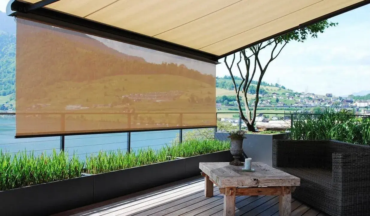 Terrasse mit Ausblick: Sonnenschutz-Markisen bieten Schatten. Ein rustikaler Tisch und ein Sessel laden zum Verweilen ein.