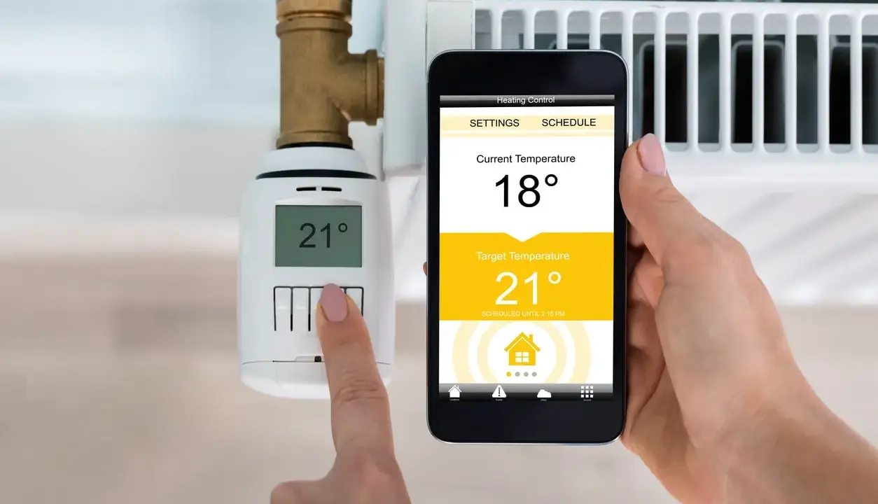 Heizung im Sommerbetrieb: Smartphone zeigt 18°C an, Zieltemperatur 21°C. Thermostat am Heizkörper zeigt 21°C.