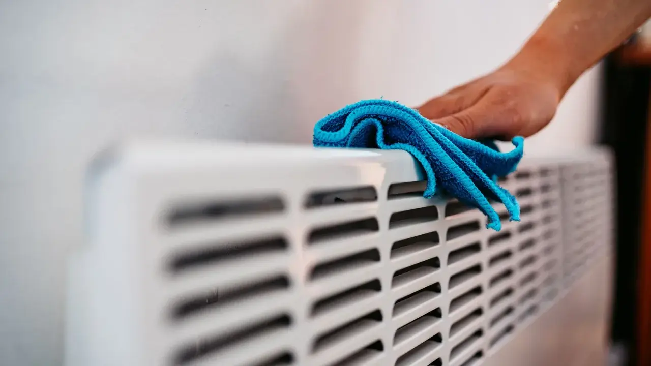 Hand wischt über Heizkörper. Die Heizung wird nicht warm, Rohre kalt.