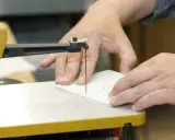 Präzises acrylglas schneiden mit einer Stichsäge. Hände führen das Material entlang der roten Schnittlinie.