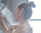Eine Frau duscht unter einem Wasserstrahl.