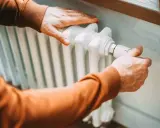 Hände stellen Heizung ein. Der Heizwert von Erdgas sorgt für wohlige Wärme im Haus.