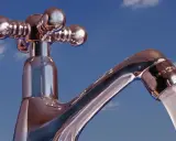Chromhahn mit laufendem Wasser vor blauem Himmel. Der Wasserdruck ist gut, die **druck wasserleitung** liefert kräftig.