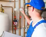 Techniker prüft Heizungsanlage, um das Heizung Wasser ablassen zu können. Er kontrolliert Manometer an Kupferrohren.