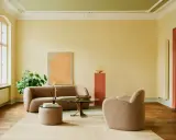 Ein Wohnzimmer mit gelben Wänden und einer grünen Decke, die frisch gestrichen wurde. Gemütliche Bouclé-Möbel und ein runder Couchtisch laden zum Verweilen ein.