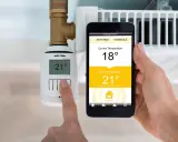 Heizung im Sommerbetrieb: Smartphone zeigt 18°C an, Zieltemperatur 21°C. Thermostat am Heizkörper zeigt 21°C.