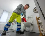 Klempner mit Saugglocke versucht, das verstopfte Klo zu befreien.