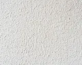 Eine weiße Wand mit feinem Rollputz auf Tapete. Die Struktur ist unregelmäßig und erzeugt ein lebendiges Oberflächenbild.