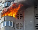 Wohnung nach Brand unbewohnbar: Flammen und Rauch steigen aus einem Balkon eines Mehrfamilienhauses. Was tun in dieser Notlage?
