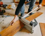 Mann nutzt einen Schneider, um Klick Vinyl zu schneiden. Werkzeuge liegen bereit.