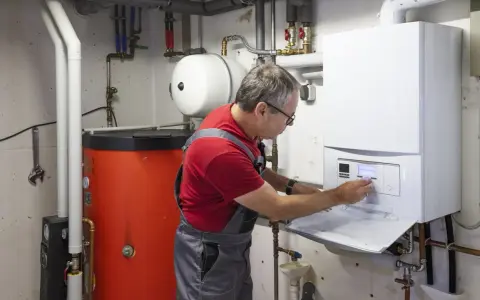 Techniker führt Abgasmessung an Heizung durch. Er bedient das Bedienfeld des modernen Brennwertgeräts.