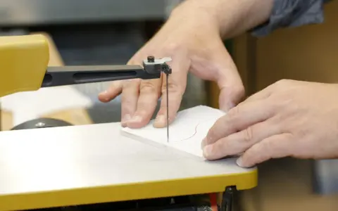 Präzises acrylglas schneiden mit einer Stichsäge. Hände führen das Material entlang der roten Schnittlinie.