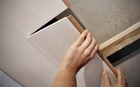 Hände bringen Deckenpaneele an, ohne Unterkonstruktion. Die Paneele werden direkt an die Decke geklebt oder geschraubt.