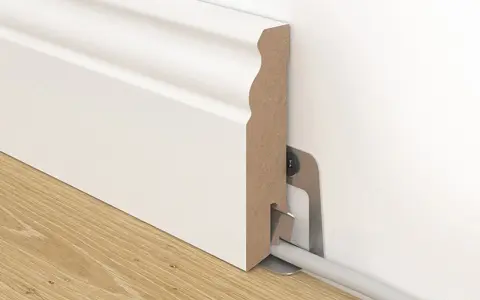 Weiße Sockelleiste mit Kabelkanal, die an der Wand befestigt ist. So kann man Leisten kleben und Kabel verstecken.