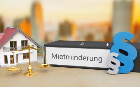 Hausmodell, Waage und Ordner mit "Mietminderung" Schriftzug. Ein Paragrafensymbol deutet auf rechtliche Aspekte hin, z.B. bei Problemen mit der Heizung.
