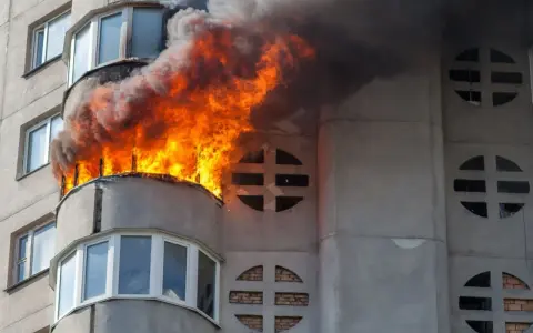 Wohnung nach Brand unbewohnbar: Flammen und Rauch steigen aus einem Balkon eines Mehrfamilienhauses. Was tun in dieser Notlage?