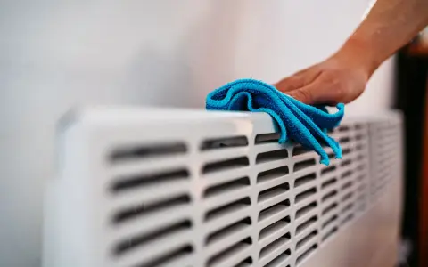 Hand wischt über Heizkörper. Die Heizung wird nicht warm, Rohre kalt.