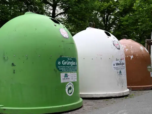 Drei Glascontainer in Grün, Weiß und Braun stehen nebeneinander. Hier kann man Fensterglas entsorgen.