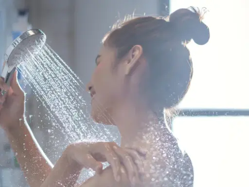 Eine Frau duscht unter einem Wasserstrahl.