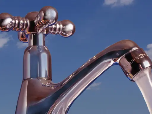 Chromhahn mit laufendem Wasser vor blauem Himmel. Der Wasserdruck ist gut, die **druck wasserleitung** liefert kräftig.