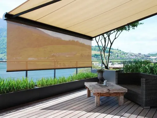 Terrasse mit Ausblick: Sonnenschutz-Markisen bieten Schatten. Ein rustikaler Tisch und ein Sessel laden zum Verweilen ein.