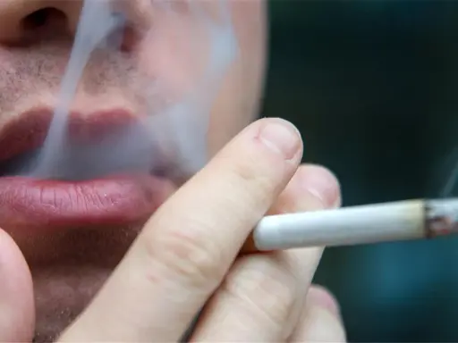 Nahaufnahme einer Person, die raucht. Der Rauch steigt auf und umhüllt die Lippen. Ein Fall von Mietminderung wegen Rauchgeruch.