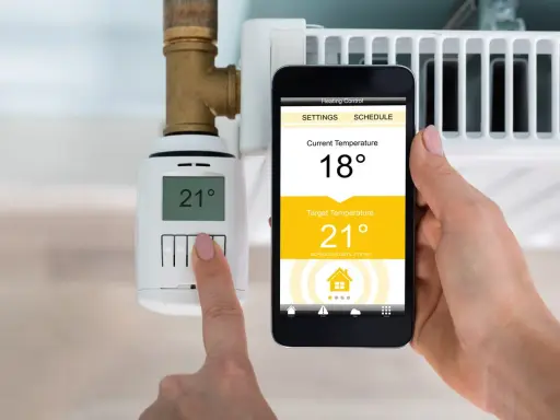 Heizung im Sommerbetrieb: Smartphone zeigt 18°C an, Zieltemperatur 21°C. Thermostat am Heizkörper zeigt 21°C.