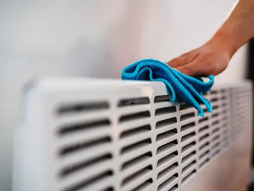 Hand wischt über Heizkörper. Die Heizung wird nicht warm, Rohre kalt.