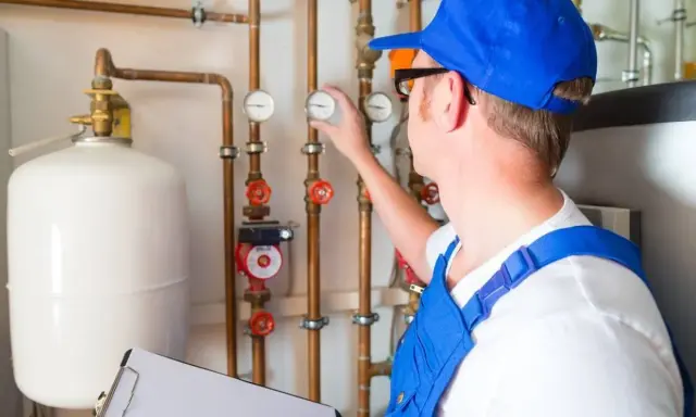 Techniker prüft Heizungsanlage, um das Heizung Wasser ablassen zu können. Er kontrolliert Manometer an Kupferrohren.