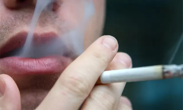 Nahaufnahme einer Person, die raucht. Der Rauch steigt auf und umhüllt die Lippen. Ein Fall von Mietminderung wegen Rauchgeruch.