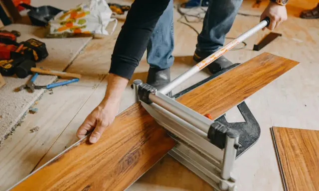Mann nutzt einen Schneider, um Klick Vinyl zu schneiden. Werkzeuge liegen bereit.