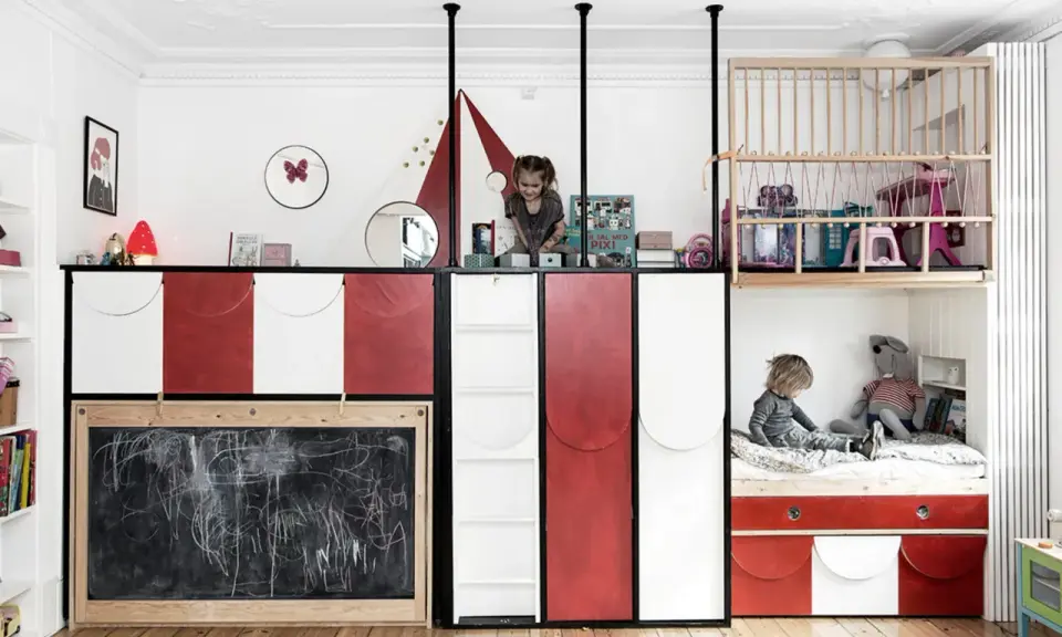 Kreatives Kinderzimmer mit wenig Platz: Zwei Kinder spielen auf verschiedenen Ebenen, eine Tafel und ein Hochbett mit Spielzeug.