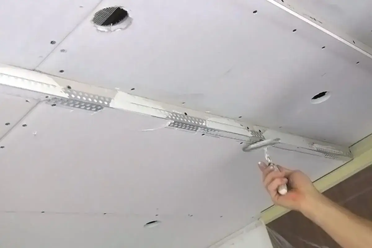 Hand glättet mit Spachtel die Decke, um Gipskarton zu verputzen.