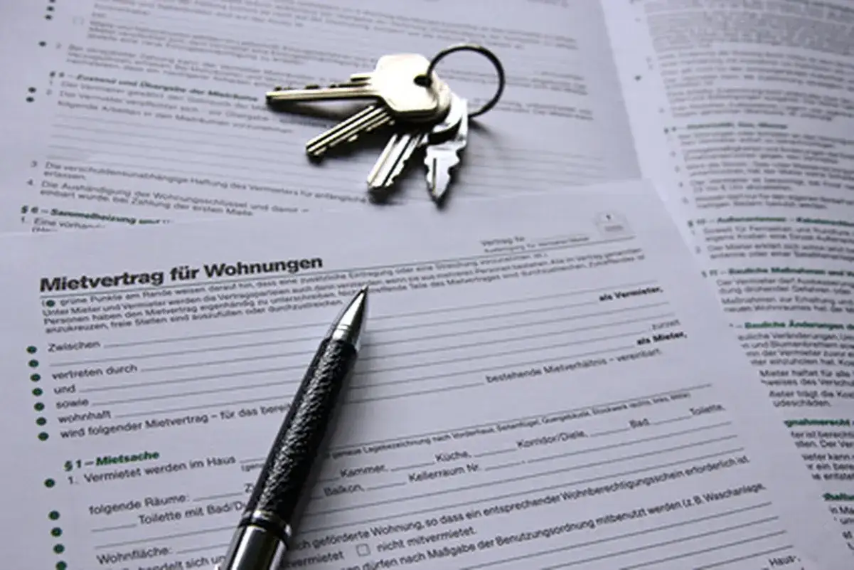 Schlüssel und Stift liegen auf einem Mietvertrag. Ein Aufhebungsvertrag für den Mietvertrag ist hier nicht zu sehen, aber die Dokumente deuten auf eine Wohnungsübergabe hin.
