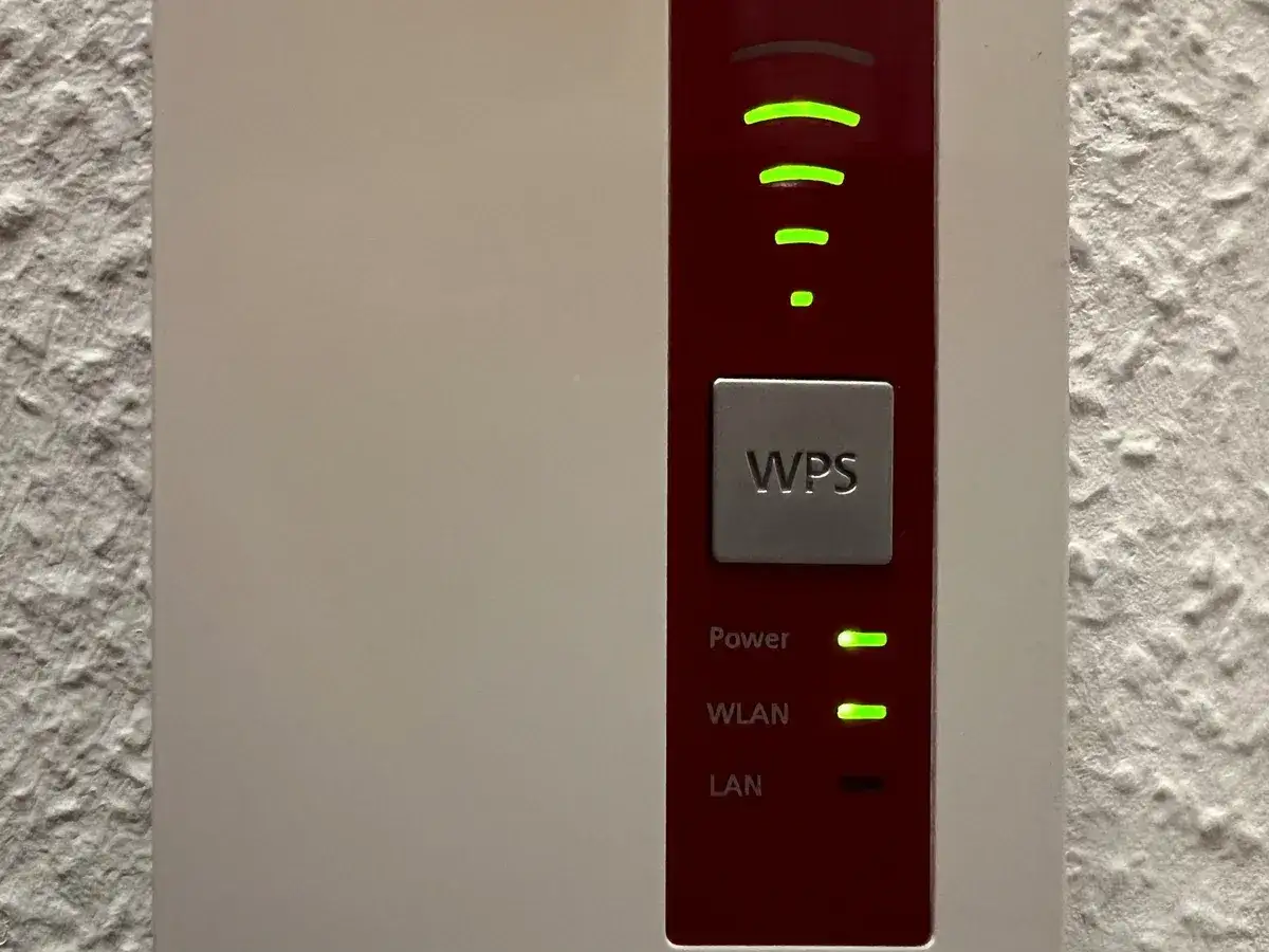 WPS-Taste an einem Router. Grüne Lichter zeigen WLAN-Signalstärke und Power an.