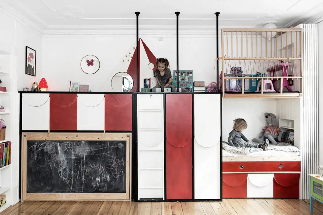 Kreatives Kinderzimmer mit wenig Platz: Zwei Kinder spielen auf verschiedenen Ebenen. Unten eine Tafel, oben ein Bett und Spielbereich.