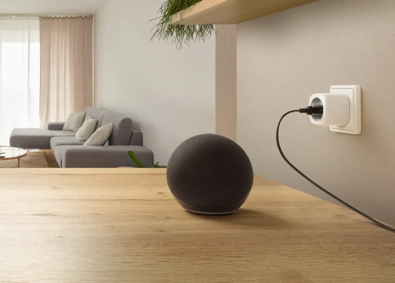 Ein Alexa Matter-Gerät auf einem Holztisch, bereit, das Smart Home zu steuern. Im Hintergrund ein Sofa und Vorhänge.